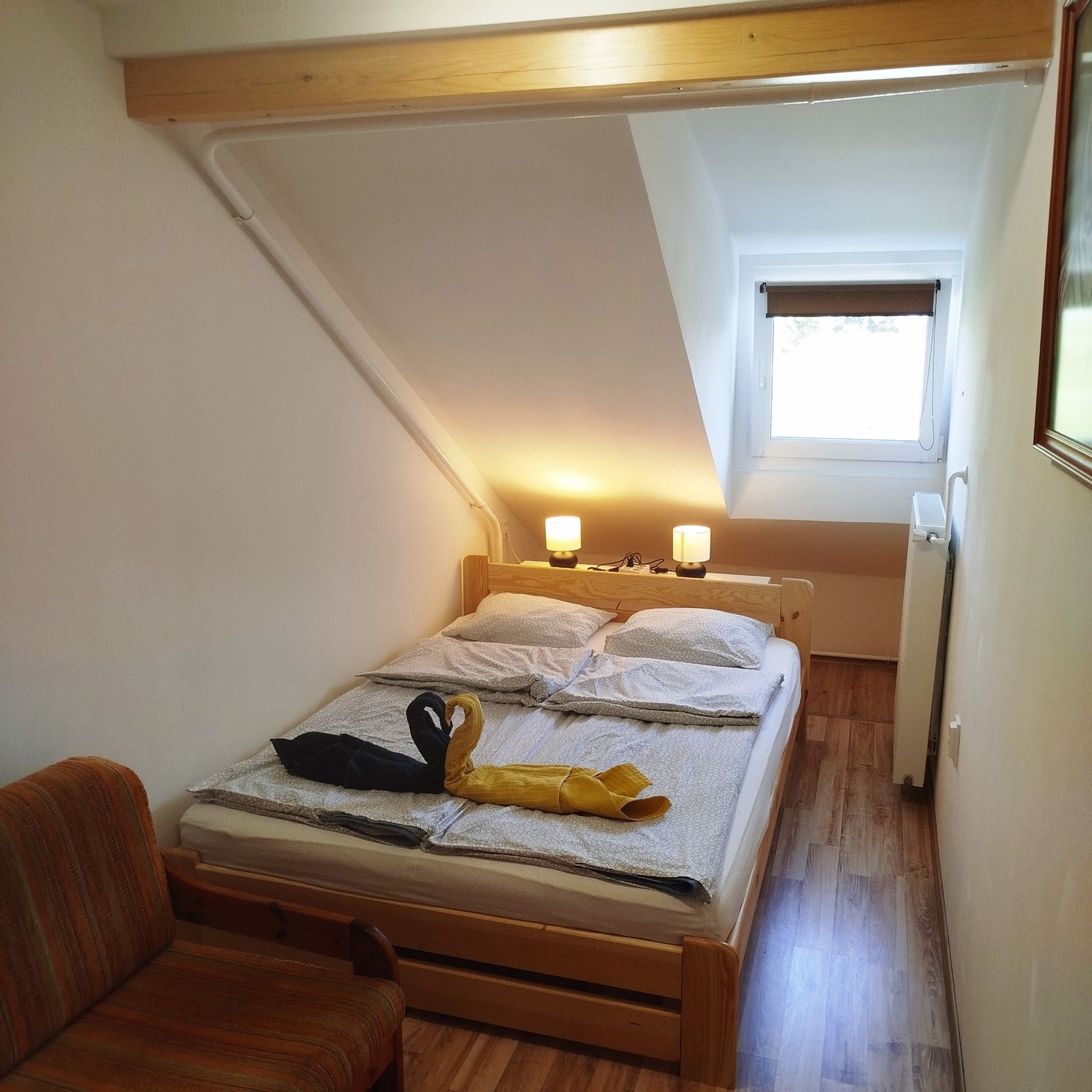 Tetőtéri apartman hálószobája, ferde tetőtéri mennyezettel
